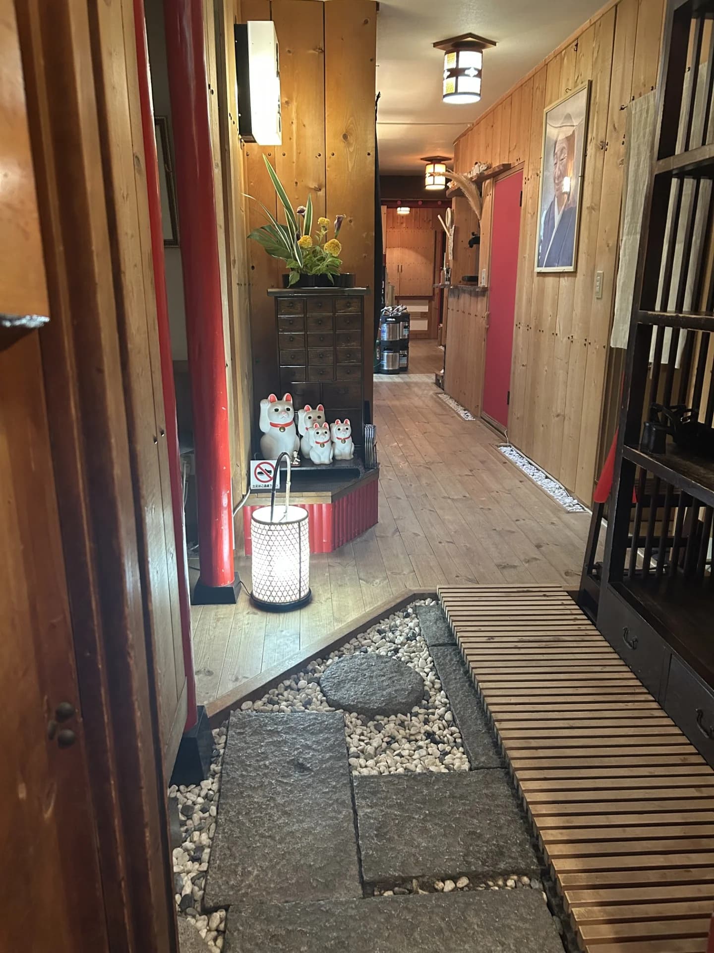 木の壁に招き猫と行灯が並び、石畳の玄関から奥へ続く和香の店内通路
