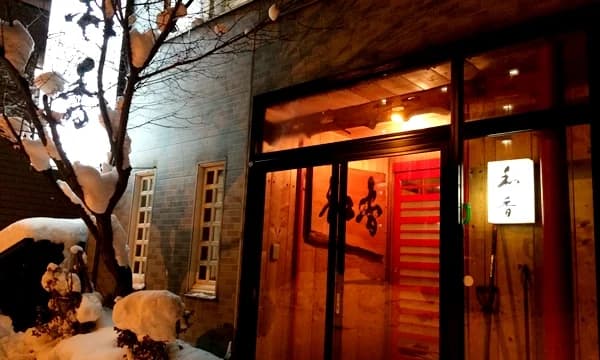 雪の夜に入口と行灯看板が灯る和香の店構え